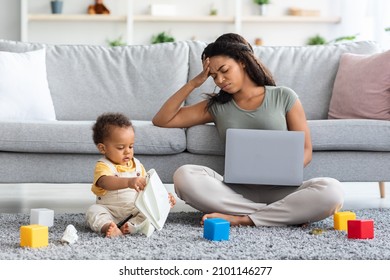 Motherhood Challenges. Stressed Black Woman Trying To Work On Laptop With Little Baby Boy Playing Around, Annoyed Mom Suffering Troubles With Remote Job While Babysitting Her Infant Child, Free Space