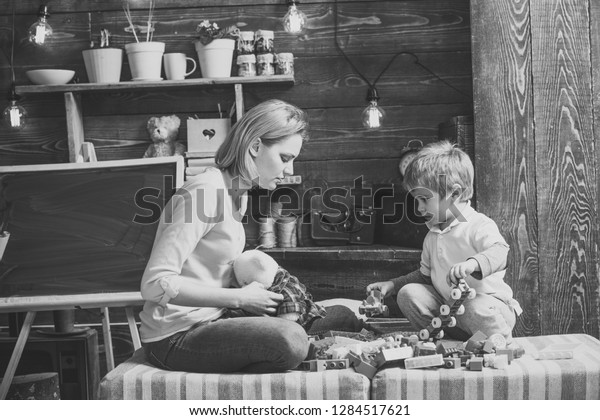 Motherhood concept. Family play with\
constructor at home. Mom and child play with details of\
constructor, plastic bricks. Nursery with chalkboard on background.\
Mother and son play with\
constructor.