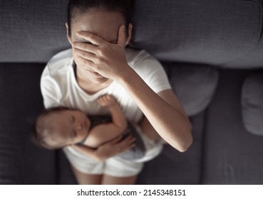 motherhood, multi-tasking and family concept. Tired mother having headache, stressed with baby child at home