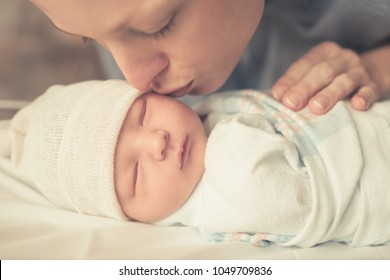 Motherhood, and parenting. Mother kissing her sleeping baby boy on cheek.  - Powered by Shutterstock