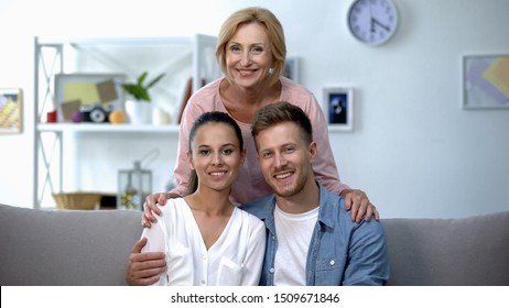 Mother-in-law embracing son and his wife, happy family relationship concept