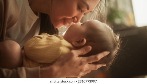 Motherly Affection Concept: Close Up Portrait of an Asian Woman New to Motherhood Having Special Moment with Infant. Cute Baby Smiling and Enjoying Bonding Time Together, Looking at Mother with Love - Powered by Shutterstock