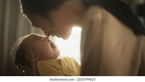 Motherly Affection Concept: Close Up Portrait of a Cute Asian Baby Laughing and Enjoying Bonding Time Together, Looking at Mother with Love. Woman New to Motherhood Having Special Moment with Infant - Shutterstock ID 2310794025