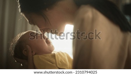 Motherly Affection Concept: Close Up Portrait of a Cute Asian Baby Laughing and Enjoying Bonding Time Together, Looking at Mother with Love. Woman New to Motherhood Having Special Moment with Infant