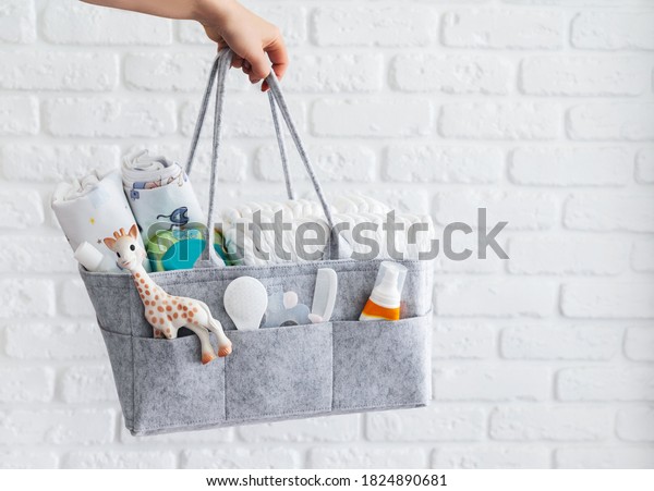 Mothers bag with toy, diapers and\
accessories on white\
background\
