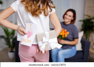 mothers day or birthday concept - daughter making surprise for mother holding gift box and handmade greeting card behind the back - Powered by Shutterstock