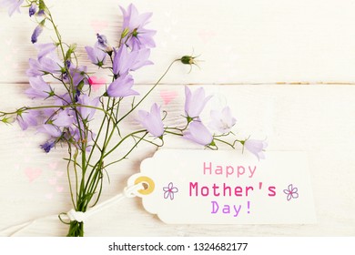 Mothers Day Card With With A Bouquet Of Delicate Wildflowers Campanula On White Wooden Board. Overhead Top View, Flat Lay. Copy Space