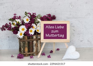 Mother's Day card: Chalkboard with Mother's Day greetings in front of a flower arrangement with lilacs and daisies. German inscription means Happy Mother's Day. - Powered by Shutterstock