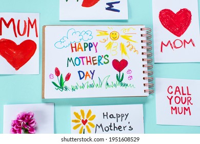 Mothers day cards made by a child. Many different postcards laid out on a blue minimal background for mom day