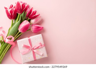 Mother's Day celebration concept. Top view photo of giftbox with ribbon bow and bouquet of pink tulips on isolated pastel pink background with copyspace - Powered by Shutterstock