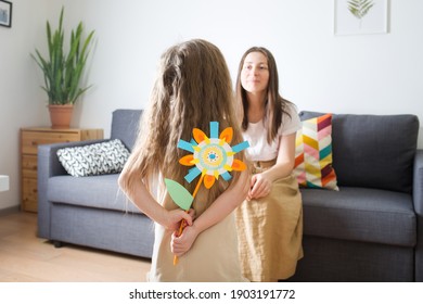 Mother's Day. Child Gives Her Mom Flower Made Of Paper. Baby Girl. Girl Hides Craft In Her Hands. Diy Create Art For Kids