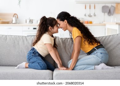 Mother's Day Concept. Cheerful Arab Mother And Her Cute Little Daughter Bonding At Home, Joyful Middle Eastern Mom And Female Child Having Fun Together, Touching Foreheads And Laughing, Side View