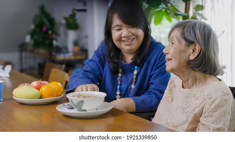 Muttertag, Tochter, die ältere Mutter mit Suppe ernährt.