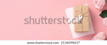 Mother's Day design concept background with pink rose flower and wrapped kraft gift box on pink table background.