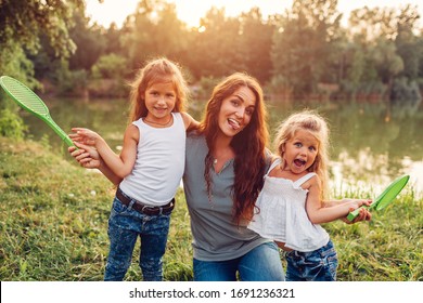 Mothers Day. Family Having Fun After Playing Badminton In Spring Park. Woman Laughing And Grimacing With Kids