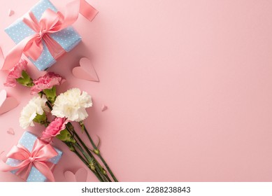Mother's Day gift concept. Top view of elegant present boxes with pink ribbon, pretty carnation flowers, and cute paper hearts on a pastel pink background with space for text or branding - Powered by Shutterstock