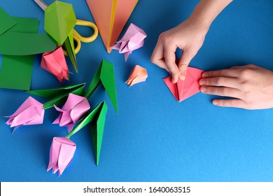 Mother's day gift. Hands of a child.  Happy birthday, March 8, Women's Day, Valentine's Day. Bouquet of tulips from origami colored paper on a blue background. copy space. Flat lay