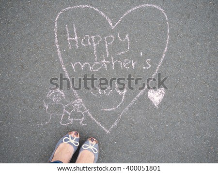 Mothers day - heart shape chalk drawing with text message and the feet of a woman on the asphalt ground