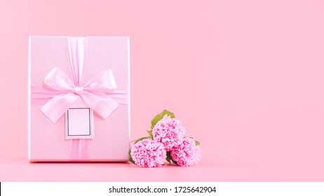 Mother's Day Holiday Gift Design Concept, Pink Carnation Flower Bouquet With Wrapped Box Isolated On Light Pink Background, Copy Space.