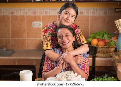 Mother's Day. Mother and daughter in the kitchen smiling at the camera.