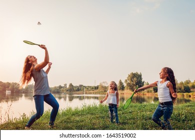 Mother's Day. Woman Playing Badminton And Having Fun With Daughters In Summer Park. Family Time