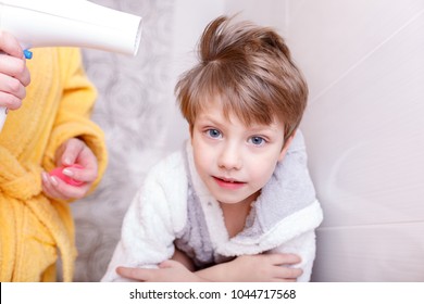 Mothers Drying Her Beautiful Boy With A Hair Dryer After A Bath. Toddler Laughing, Joking And Playing With The Hairdryer That Is Blowing His Hair