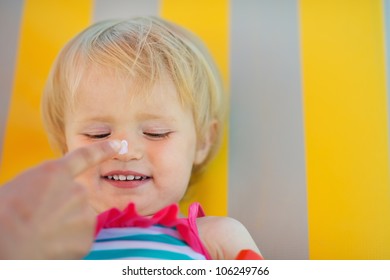 Mother's Hand Applying Sun Block Creme On Baby Nose