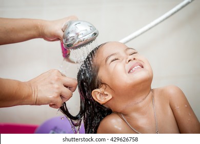 Mother's Hand Pours Water From Shower To Wash Little Girl's Hair