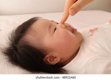 Mother's Hand Touching Cute Asian Baby Girl On Her Button Nose