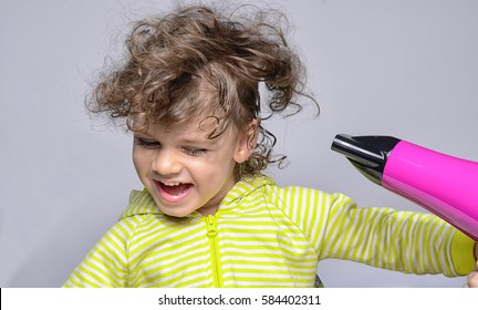 Mothers Hands Drying Her Beautiful Boy After A Bath. Toddler Laughing, Joking And Playing With The Hairdryer That Is Blowing His Curly Hair