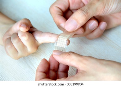 Mother's Hands Putting A Plaster On Child Finger 