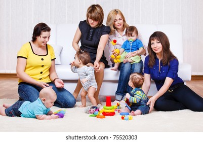 Mothers in the living room look at their babies playing