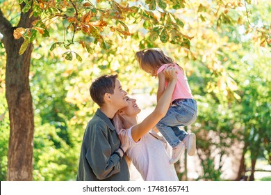 Mothers Looking At Her Daughter And Adoring Her. Lesbian Couple Are Really Happy To Adopt A Child. LGBT Family In The Park.