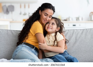 Mother's Love. Portrait Of Tender Young Arab Woman Hugging Her Cute Little Daughter While Relaxing On Couch At Home, Loving Mom Bonding With Female Child, Enjoying Time Together, Copy Space - Powered by Shutterstock