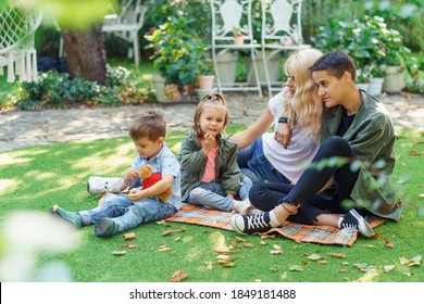 Mothers Resting With Kids In The Park. Lesbian Couple Sitting With Their Son And Daughter On A Plaid. LGBT Parenting Concept.