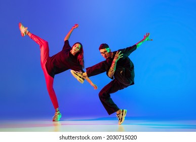 Motion, Action. Two Young People,man And Woman Dancing Contemporary Dance Over Blue Background In Neon Light. Youth Culture, Modern Dance Aesthetics Concept