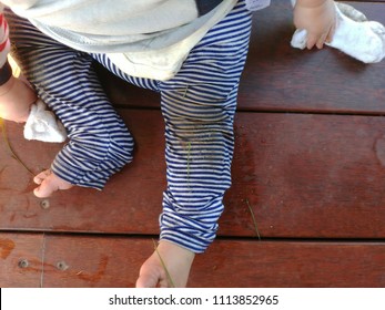 Motion Blur, Baby Legs After Play On The Ground, Infant Pants Are Very Dirty With Grass And Dirt. Kid Pull Off The Sock To Play On The Floor