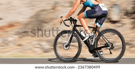 Motion blur of a bike race with the bicycle and rider at high speed. Professional female cyclist in racing in triathlon clothing outfit during a ride on bike outdoors. Panning technique used