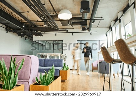 motion blur of business partners walking in lounge of contemporary coworking environment with high tech interior, modern furniture and natural plants, dynamic business and productivity concept