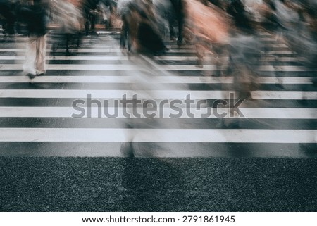 Motion blur captures the fast pace of urban life as people cross a busy street at a zebra crossing.