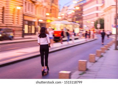 Motion Blur Effect. Girl Riding Electric Step Scooter In City Center Of Prague. People Riding Electric Scooter At Night. Photo With Motion Blur Effect In Prague, Czech Republic.