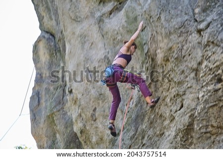 Motion blur image of young woman climber falling down after failed attemp to climb steep wall of rocky mountain. Engaging in extreme sport concept.