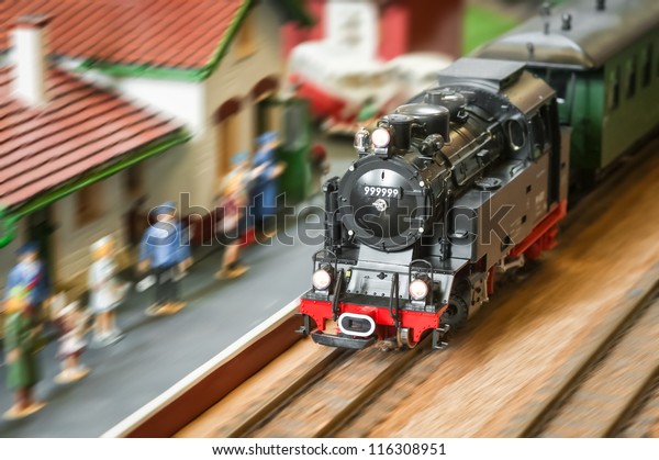 motion blur of a model\
railroad steam locomotive (with fake number) speeding through a\
station