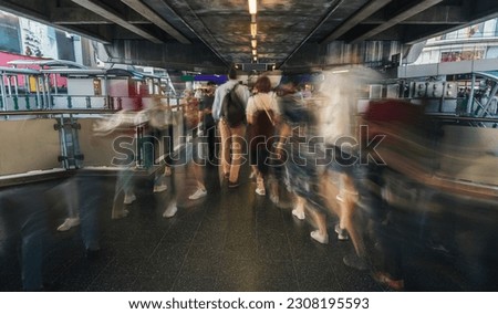 Motion blur of moving busy crowd of walking people in Bangkok city in aboveground pedestrian crossing to subway station at rush hour in the evening. City life cinematic urban concept