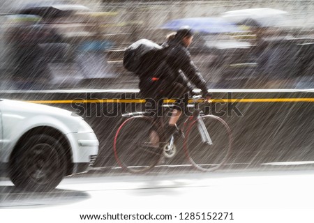 motion blur picture of a cyclist in the traffic of a city street at heavy rain