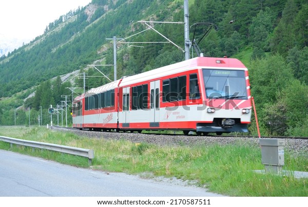 Motion blur picture and noise effect of red\
train at the railway from\
Zermatt.