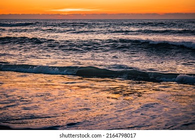 Motion blur sea foam with sunset colors reflected in water and lowlight waves breaking, PORTUGAL