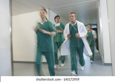 Motion Blur Shot Of Doctors And Nurses In Scrubs Running Through Hospital Corridor