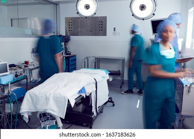 Motion Blur Shot Of Surgical Team Wearing Scrubs In Busy Hospital Operating Theater