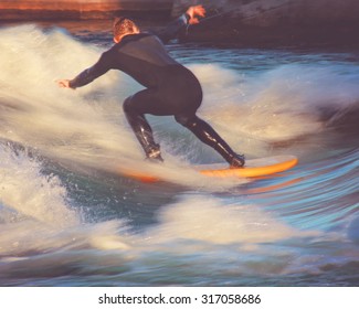 motion blur of a surfer riding a wave in a full wet suit toned with a retro vintage instagram filter app or action effect (SHALLOW DOF action shot)  - Powered by Shutterstock